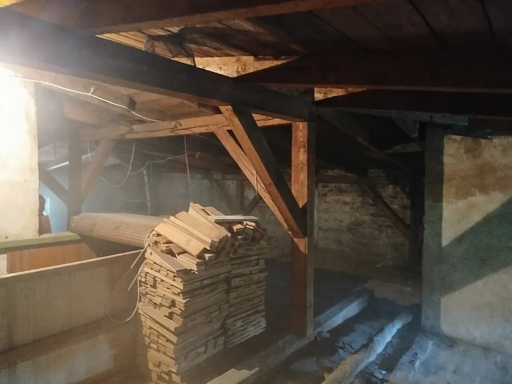 Stos płyt i kartonów złożony pod skosem dachu na strychu