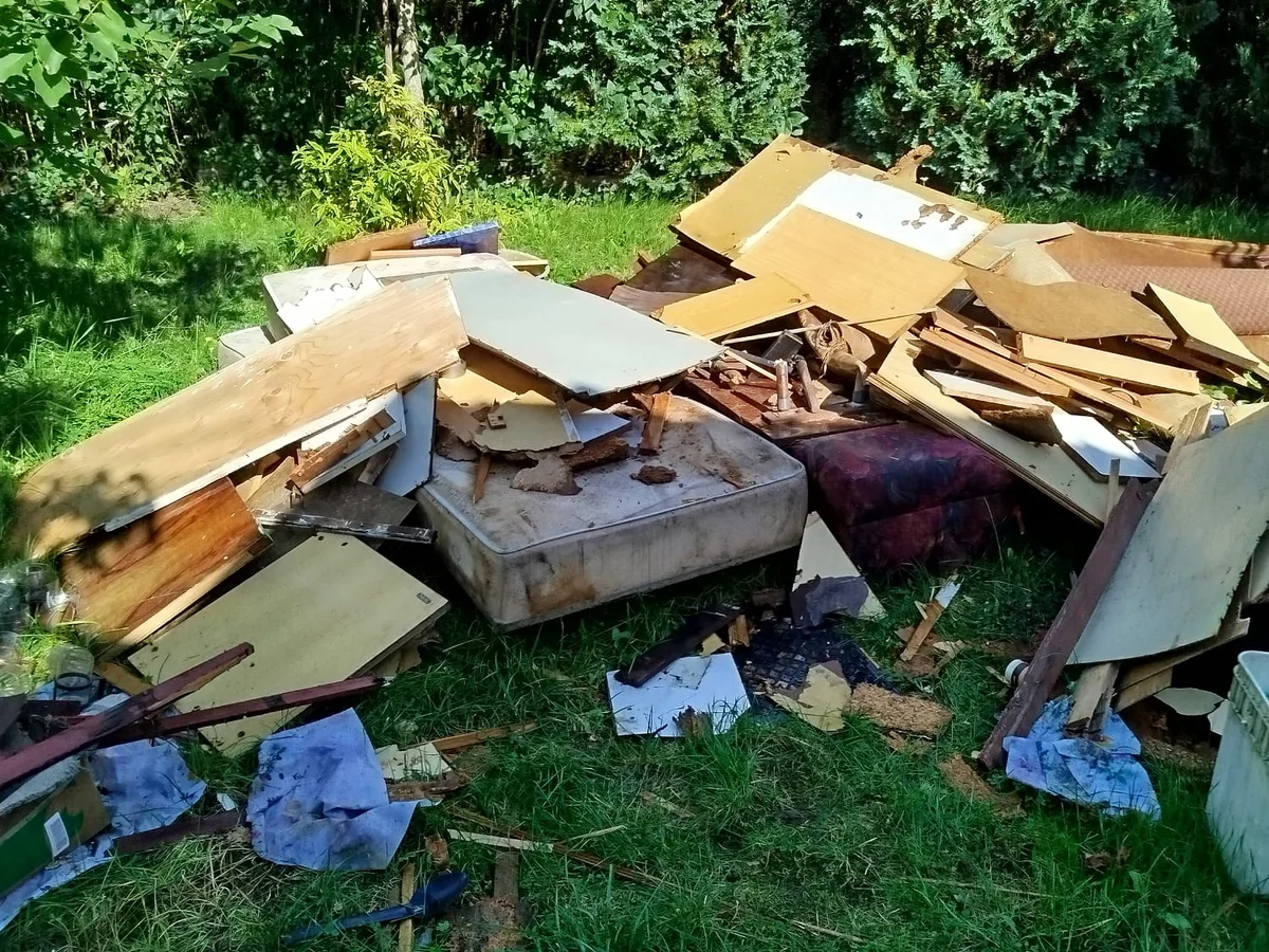 Sterta płyt meblowych, szuflad i starego materaca wyniesionych z altany na trawnik